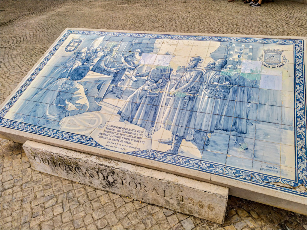 história da cidade de faro representada em azulejo frente às muralhas da cidade que circundam o centro histórico