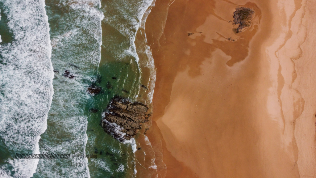 Detalhe da praia do Medo da Fonte Santa visto do ar: formações rochosas à entrada do mar.