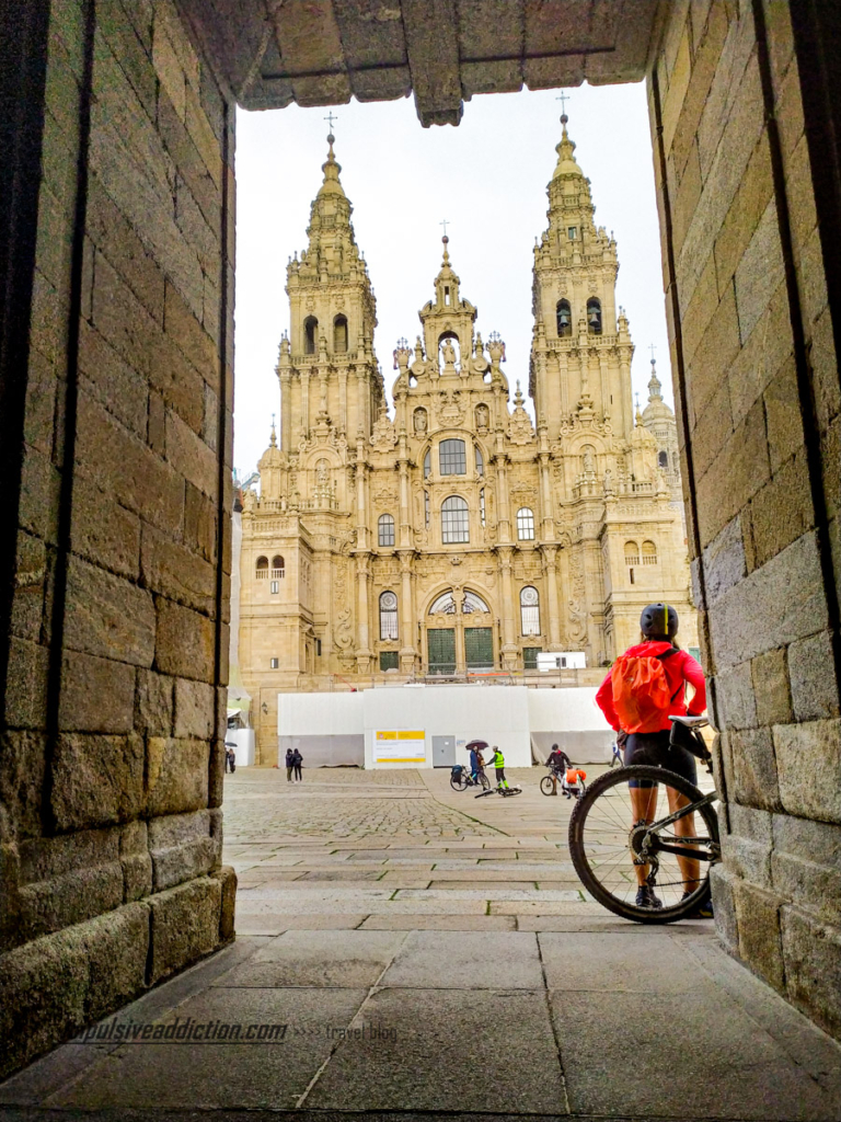 Uma peregrina do caminho de Santiago, de bicicleta, frente à Catedral